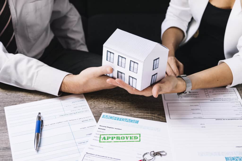 Approved home purchase documents and symbolic handover of property with paper house.